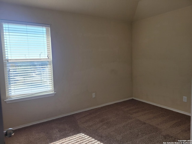 carpeted spare room with vaulted ceiling