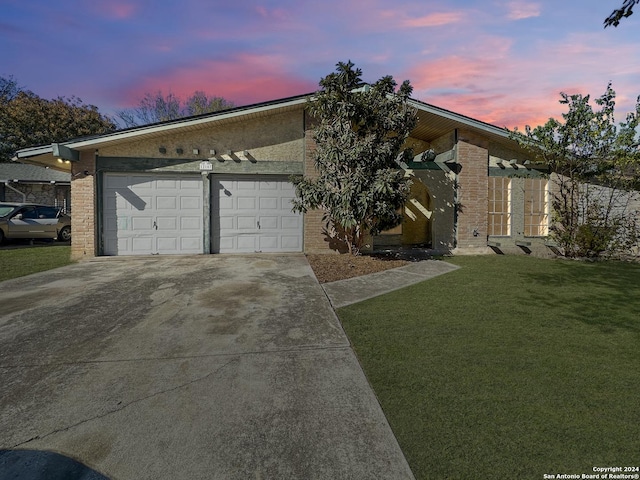 ranch-style home featuring a lawn and a garage