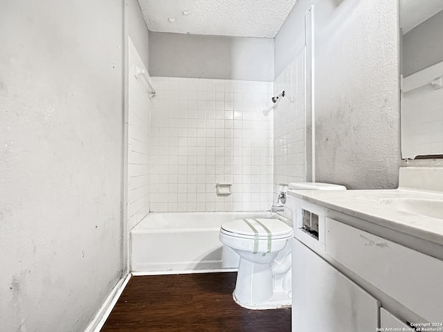 full bathroom with vanity, hardwood / wood-style flooring, tiled shower / bath combo, toilet, and a textured ceiling