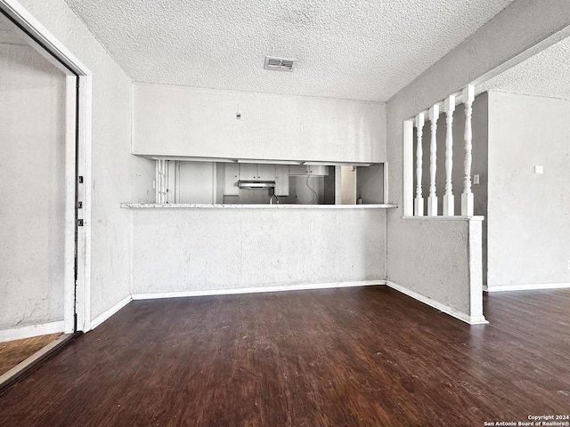 unfurnished living room with dark wood-type flooring and a textured ceiling