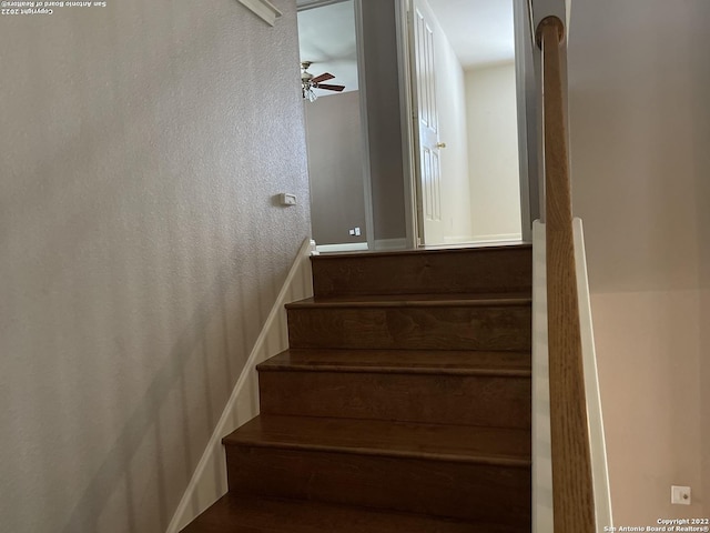 stairway featuring ceiling fan