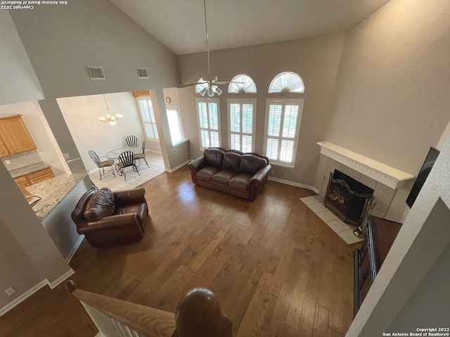 living room with a tile fireplace, ceiling fan with notable chandelier, dark hardwood / wood-style floors, and high vaulted ceiling