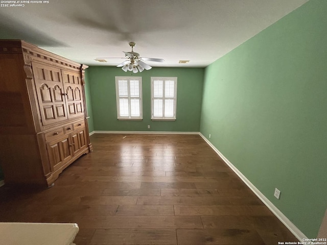 unfurnished bedroom with ceiling fan and dark wood-type flooring