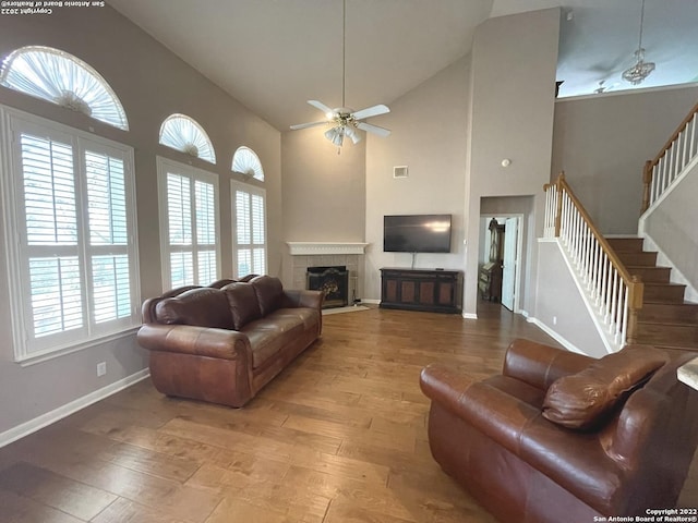 living room with a tile fireplace, high vaulted ceiling, light hardwood / wood-style flooring, and ceiling fan