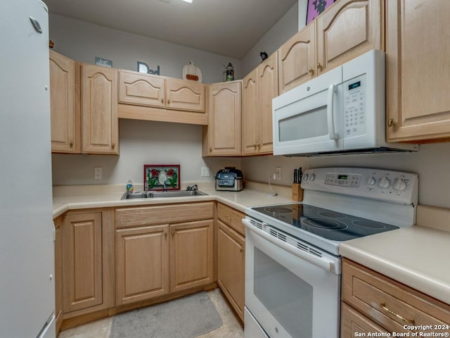 kitchen featuring light brown cabinets, white appliances, and sink