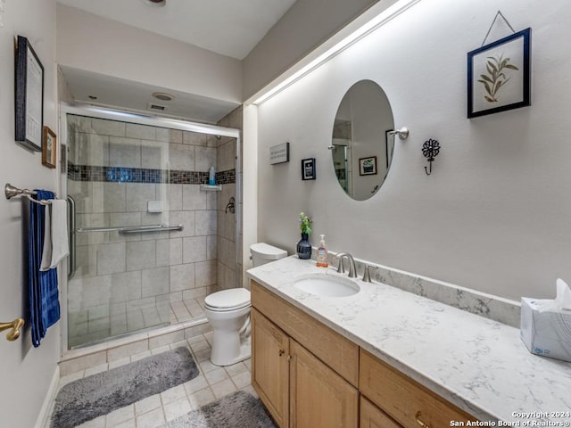 bathroom with an enclosed shower, vanity, toilet, and tile patterned flooring