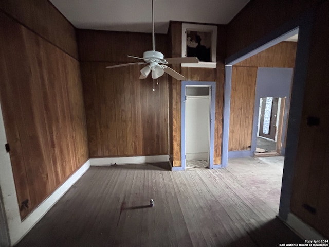 empty room with hardwood / wood-style flooring, ceiling fan, and wood walls