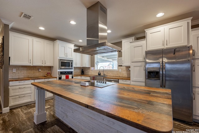 kitchen featuring wooden counters, appliances with stainless steel finishes, island range hood, dark hardwood / wood-style floors, and white cabinetry