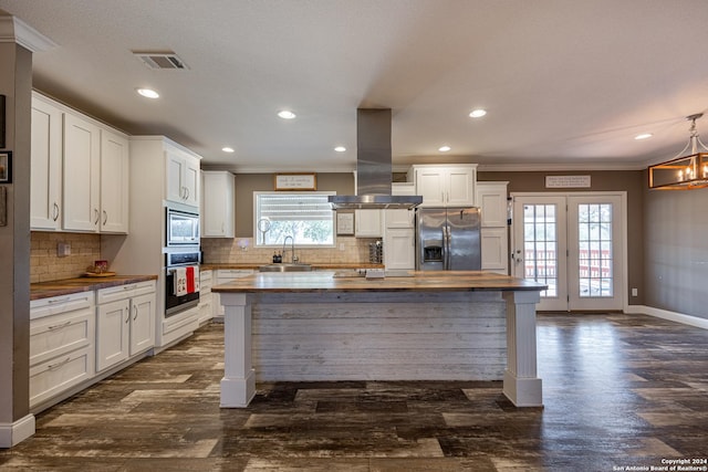 kitchen with a healthy amount of sunlight, island range hood, wooden counters, and stainless steel appliances