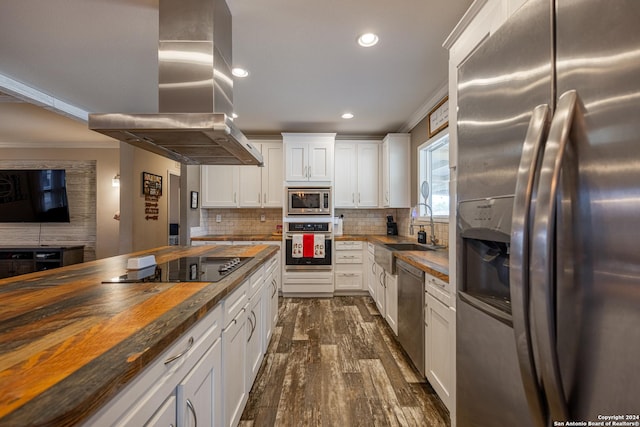 kitchen featuring white cabinets, crown molding, butcher block countertops, island exhaust hood, and stainless steel appliances