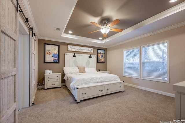 carpeted bedroom featuring ceiling fan, a barn door, a raised ceiling, and ornamental molding