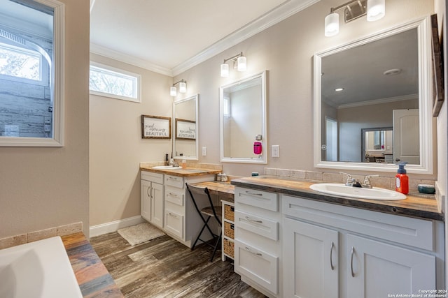 bathroom featuring vanity, a bathtub, wood-type flooring, and ornamental molding