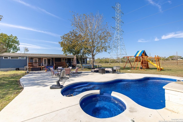 view of pool featuring an in ground hot tub, a patio, and a playground