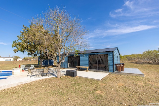 rear view of house with a patio area, a yard, an outbuilding, and a swimming pool