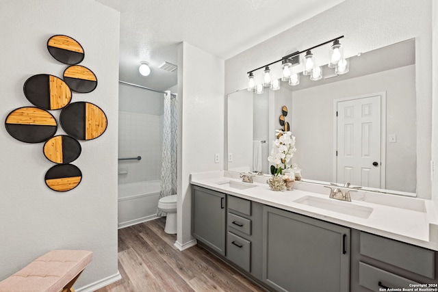 full bathroom with a textured ceiling, vanity, shower / bath combo with shower curtain, hardwood / wood-style flooring, and toilet