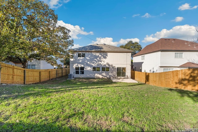 back of house with central air condition unit and a yard