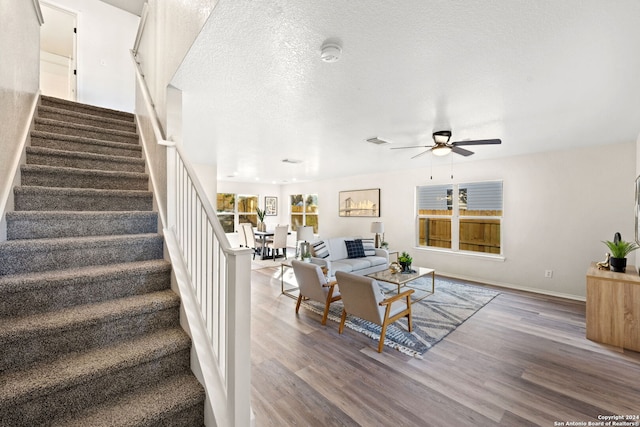 living room with ceiling fan, hardwood / wood-style floors, and a textured ceiling