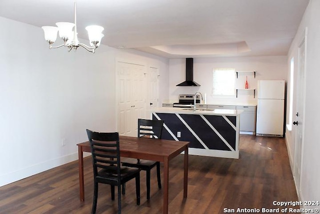 dining room featuring a tray ceiling, dark hardwood / wood-style flooring, a chandelier, and sink