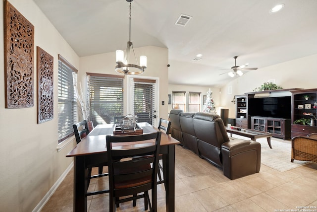 dining space with light tile patterned floors, ceiling fan with notable chandelier, and vaulted ceiling