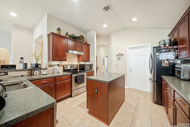 kitchen featuring a center island, light tile patterned flooring, stainless steel appliances, and vaulted ceiling