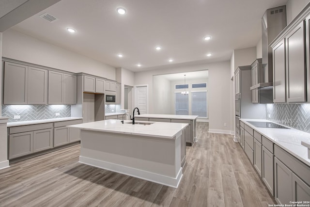 kitchen with light wood-type flooring, backsplash, black appliances, and sink