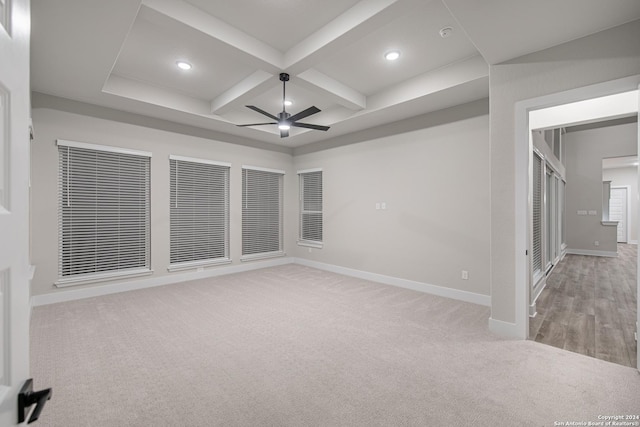 empty room featuring ceiling fan, beam ceiling, light carpet, and coffered ceiling