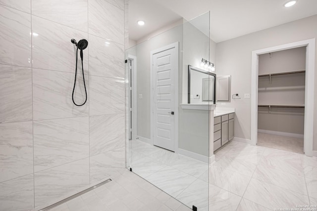 bathroom with a tile shower and vanity