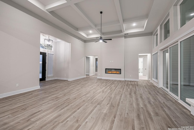 unfurnished living room featuring beam ceiling, ceiling fan with notable chandelier, and light hardwood / wood-style flooring