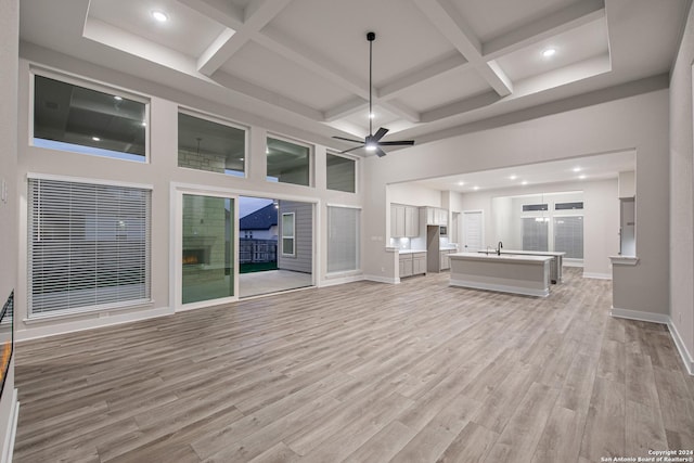 unfurnished living room with ceiling fan, light hardwood / wood-style flooring, coffered ceiling, and sink