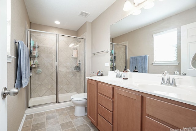 bathroom with vanity, toilet, and a shower with door