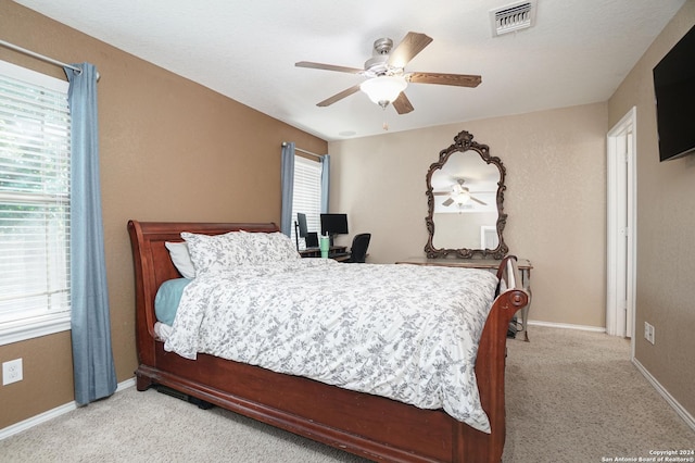 bedroom featuring light carpet, multiple windows, and ceiling fan