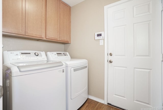 clothes washing area with dark hardwood / wood-style flooring, washer and clothes dryer, and cabinets