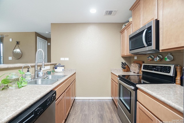 kitchen with light brown cabinets, stainless steel appliances, light hardwood / wood-style flooring, and sink