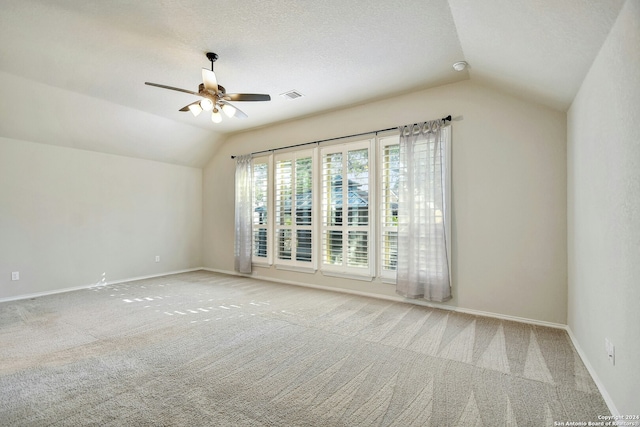 carpeted spare room featuring a textured ceiling, ceiling fan, and vaulted ceiling