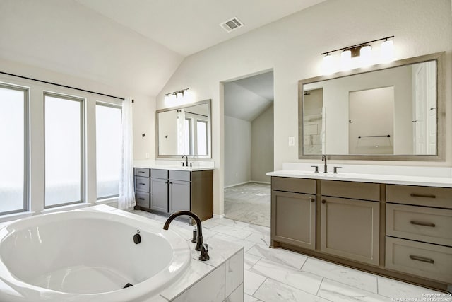 bathroom featuring vanity, lofted ceiling, and tiled tub