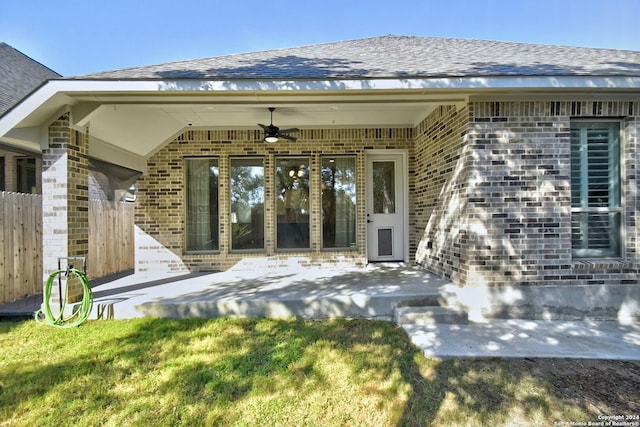 property entrance with ceiling fan, a yard, and a patio