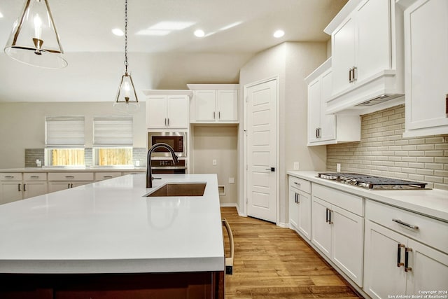 kitchen featuring pendant lighting, a kitchen island with sink, sink, light hardwood / wood-style flooring, and stainless steel appliances