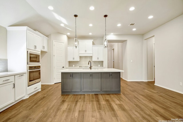 kitchen with stainless steel appliances, light hardwood / wood-style floors, gray cabinets, a kitchen island with sink, and white cabinets