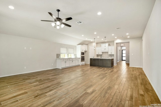 unfurnished living room featuring ceiling fan, light wood-type flooring, and lofted ceiling