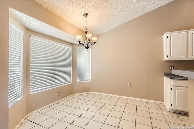 unfurnished dining area with light tile patterned flooring, a chandelier, and a textured ceiling