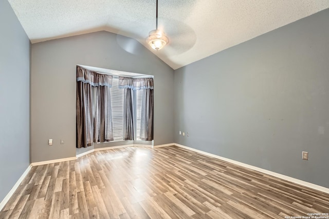 empty room with hardwood / wood-style flooring, ceiling fan, lofted ceiling, and a textured ceiling