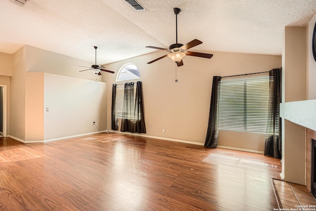 unfurnished living room with light wood-type flooring, a textured ceiling, ceiling fan, a fireplace, and lofted ceiling