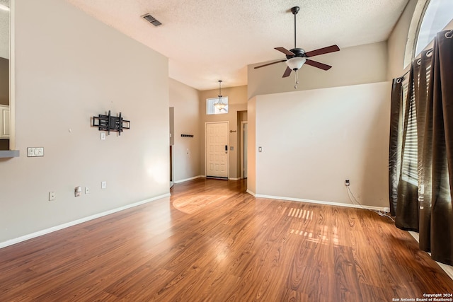 unfurnished living room with ceiling fan, high vaulted ceiling, wood-type flooring, and a textured ceiling