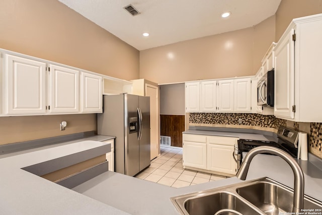 kitchen featuring appliances with stainless steel finishes, light tile patterned floors, white cabinetry, and sink