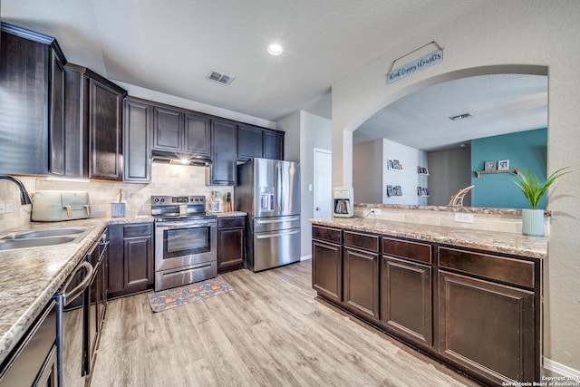 kitchen featuring backsplash, dark brown cabinets, stainless steel appliances, sink, and light hardwood / wood-style floors