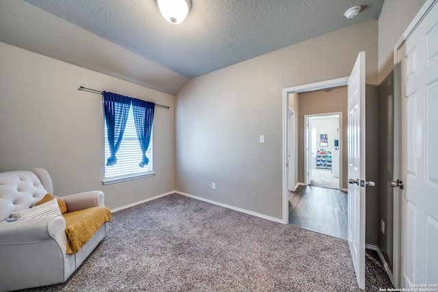 sitting room with a textured ceiling, carpet, and lofted ceiling