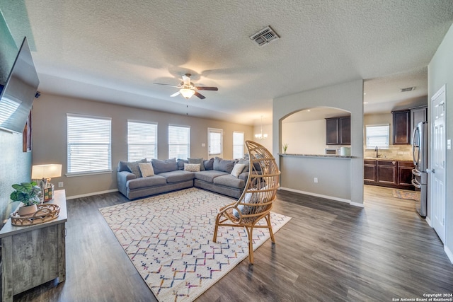 living room with a textured ceiling, ceiling fan, sink, and dark wood-type flooring