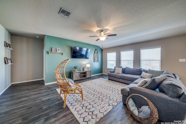 living room with a textured ceiling, ceiling fan, and dark wood-type flooring