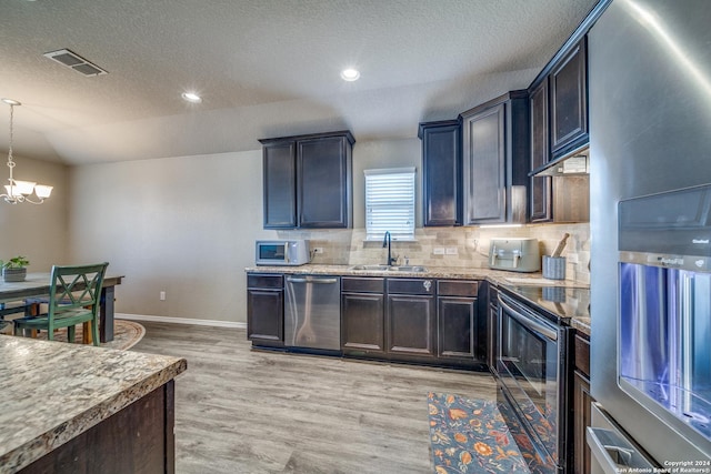 kitchen with an inviting chandelier, hanging light fixtures, sink, light wood-type flooring, and appliances with stainless steel finishes