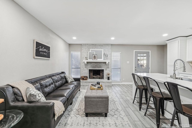 living room with a fireplace, sink, and light hardwood / wood-style floors